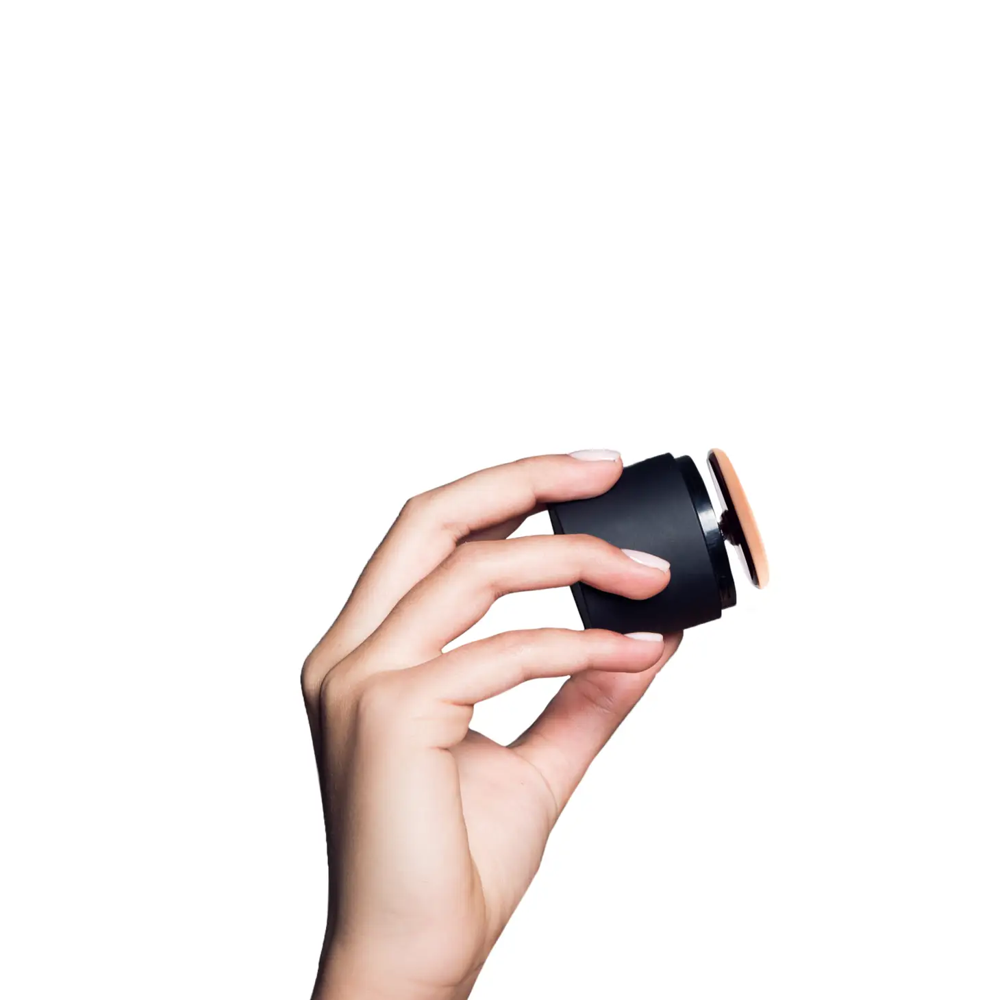 Hand hält ein schwarzes, rundes Kosmetikgerät vor weißem Hintergrund.