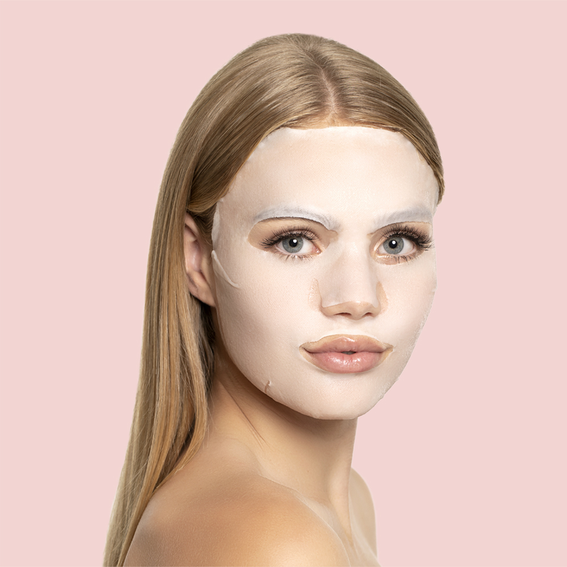 SST096_EAN7640164572468_STARSKIN-R-Orglamic-TM-Pink-Cactus-Oil-Mask_3 Frau mit blonder, glatter Frisur trägt eine weiße Gesichtsmaske vor einem rosa Hintergrund.