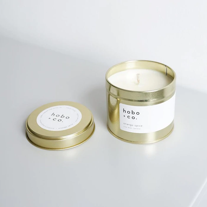 D2B0EBD9-C08D-45C6-9769-10F7139160E3 Goldene Duftkerze 'hobo + co.' mit abgenommenem Deckel auf weißem Hintergrund.