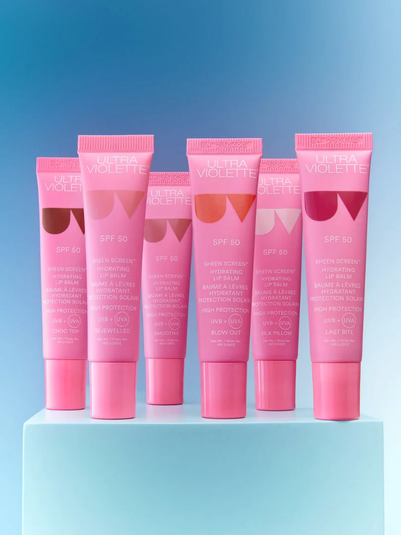 SheenScreeneCommImagery Fünf rosa Tuben Ultra Violette Sheen Screen SPF 50 Lippenbalsam auf blauem Hintergrund.