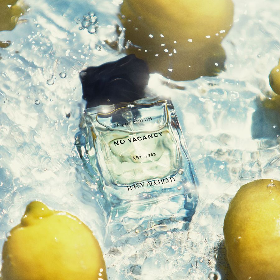 Parfümflasche 'No Vacancy' von Raw Lucifian im Wasser mit Zitronen.