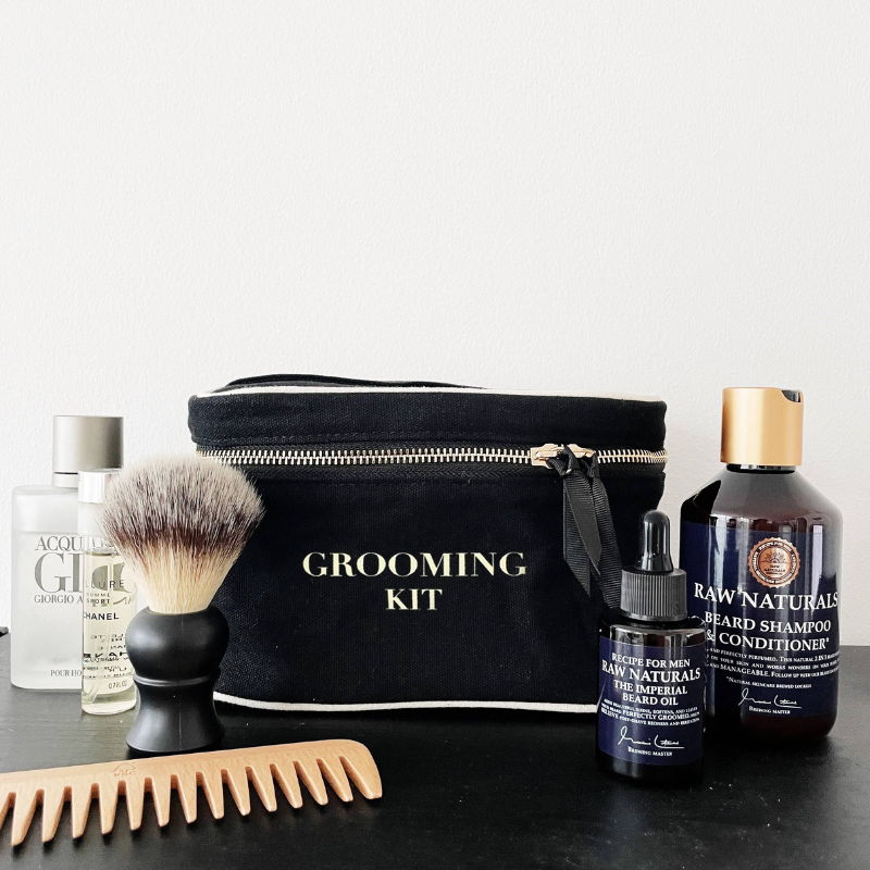 Grooming-Kit mit Kamm, Rasierpinsel, Bartöl, Bartshampoo und Conditioner vor weißem Hintergrund.