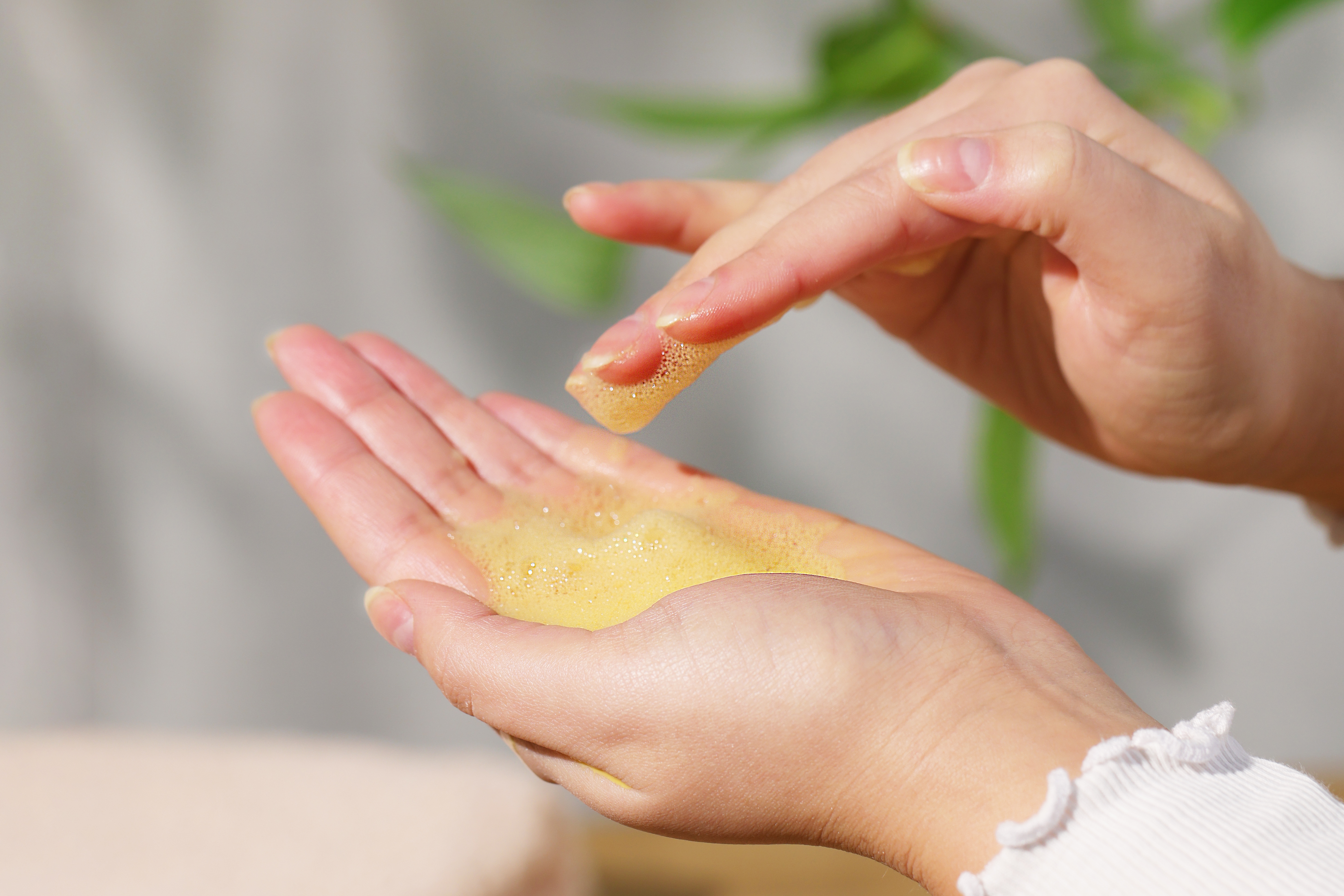 Nahaufnahme von Händen, die Enzym-Vitamin-C-Reinigungspulver aufschäumen.